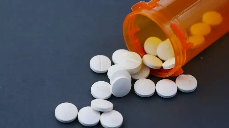 White tablets spilling from an orange prescription bottle