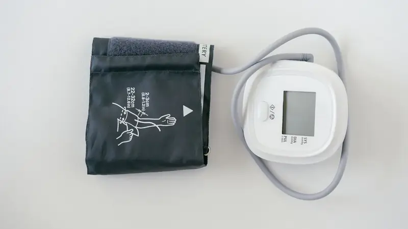 A home blood pressure monitor with its arm cuff on a white table