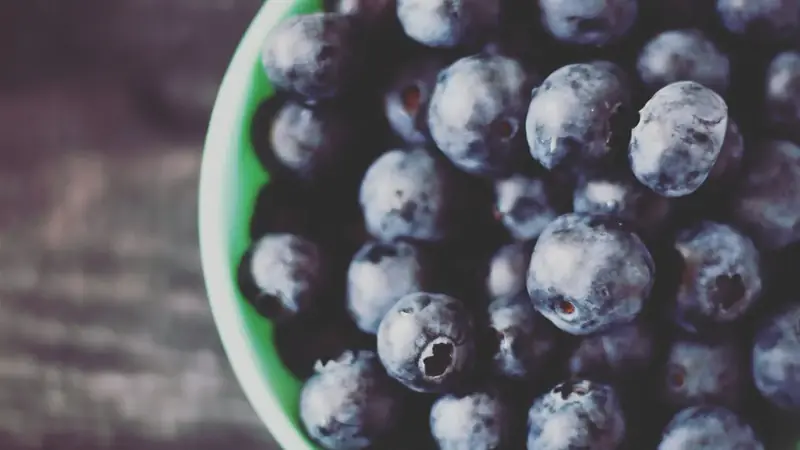 Fresh blueberries in a green ceramic bowl