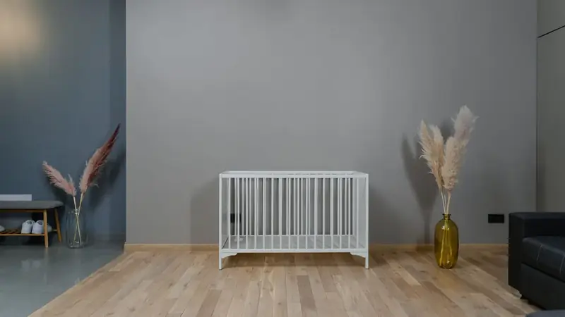 An empty white baby crib with no bedding in a minimalist nursery