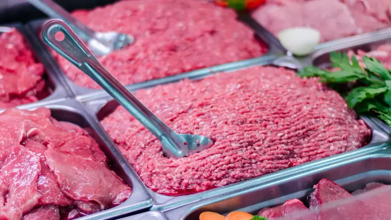 Trays of raw ground beef in a refrigerated meat display case